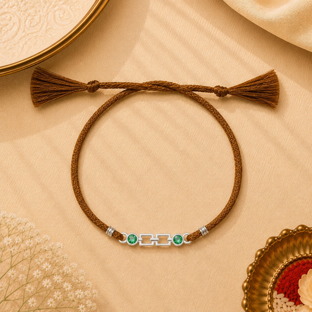 A silver cubic green stone Rakhi is placed with roli chawal and festive decor – a premium 925 silver Raksha Bandhan gift by Silviya.