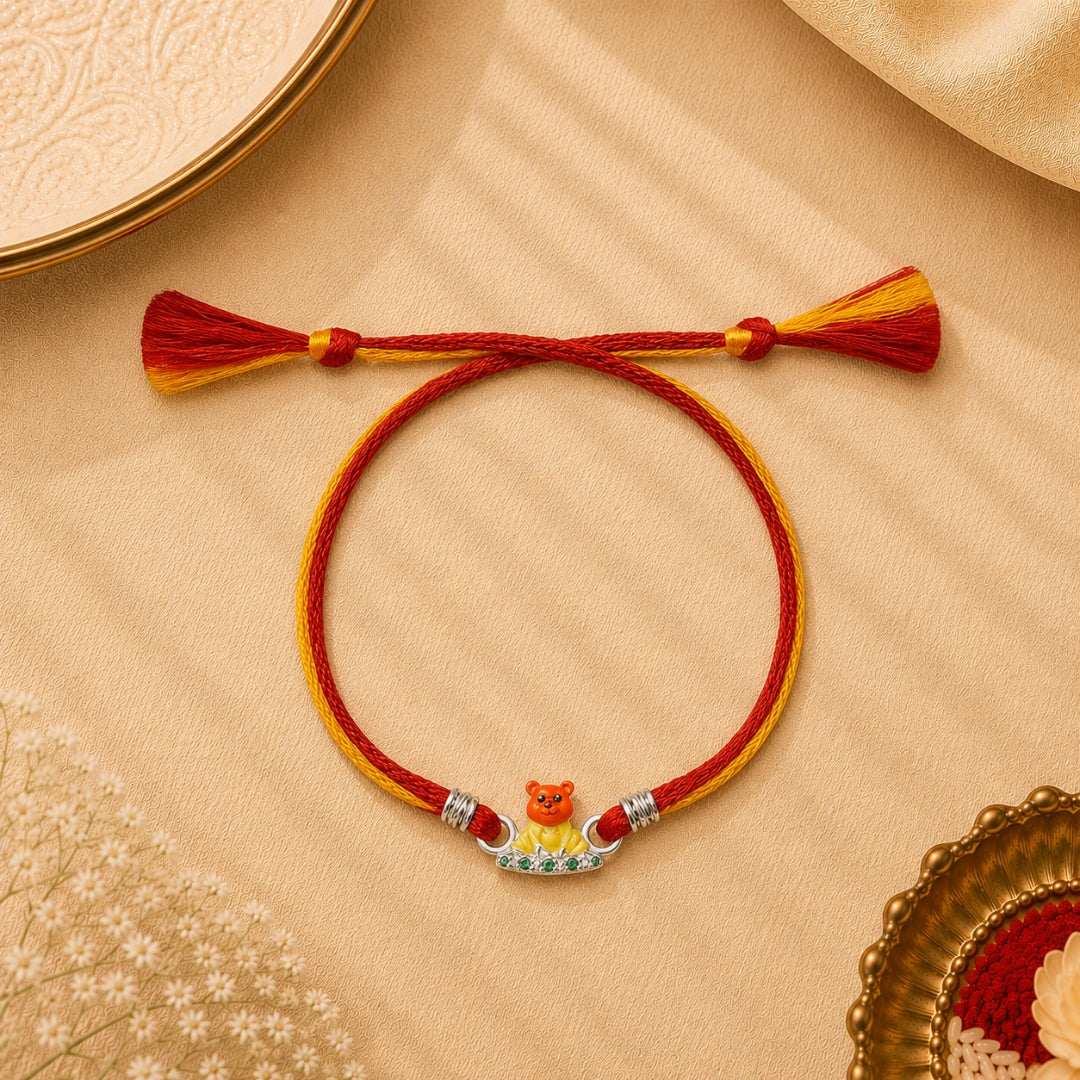 Silver Teddy Rakhi with green stones placed with roli chawal and festive decor – premium kids Raksha Bandhan rakhi by Silviya.