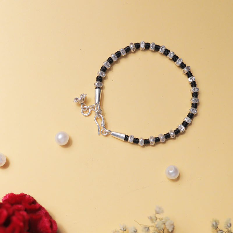 Stylish beaded silver bracelet placed on decorative background.