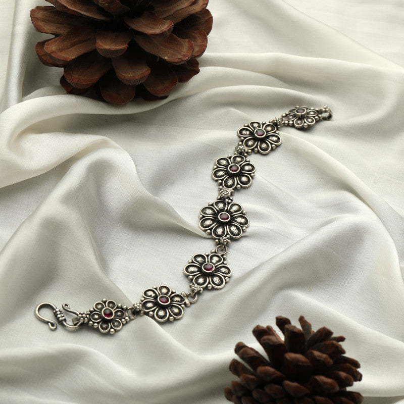 Antique silver petal design bracelet displayed on fabric background.