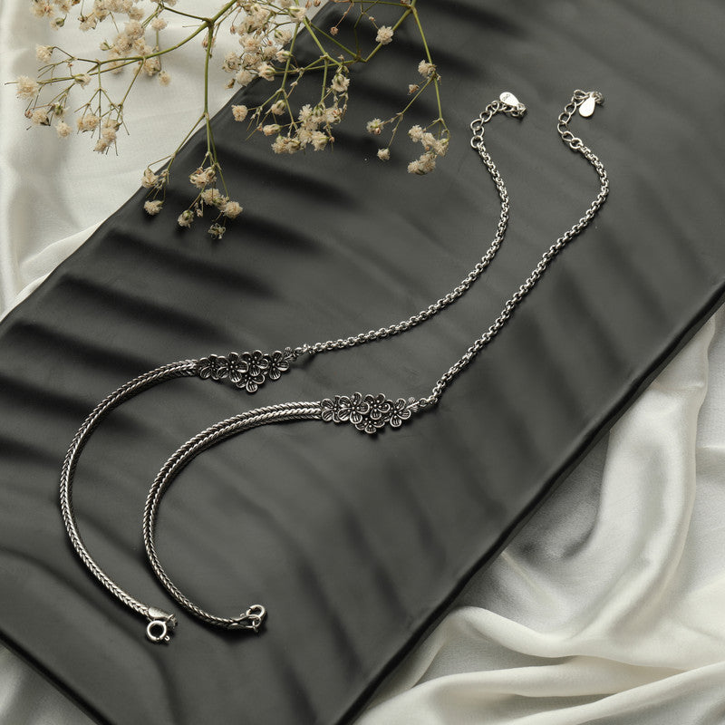 Oxidised silver anklet with minimalist charm displayed on fabric background