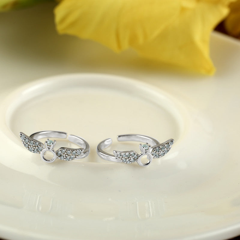 Sterling silver angel wing toe ring displayed with props – unique silver accessory