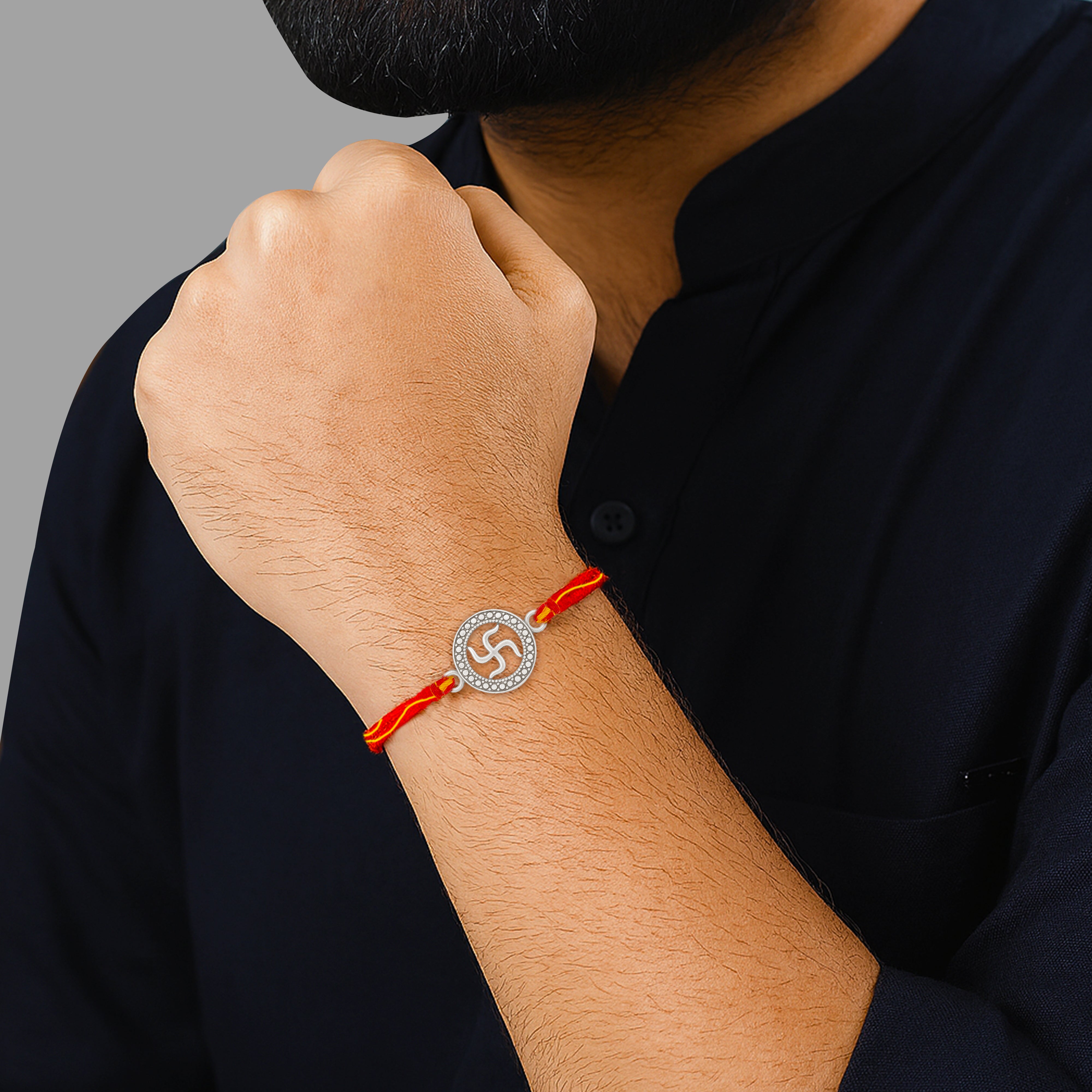 Man wearing 925 silver swastik rakhi with red thread on wrist – traditional Raksha Bandhan jewelry for brothers